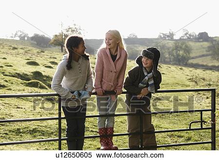 Stock Photography - Children on gate in countryside. Fotosearch