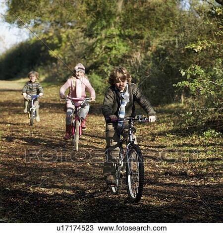 Stock Image - Children riding bikes in countryside. Fotosearch