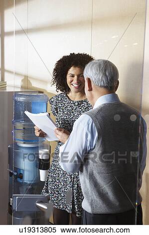 Co-workers by office water cooler View Large Photo Image Stock Photography - Co-workers by office water cooler. Fotosearch