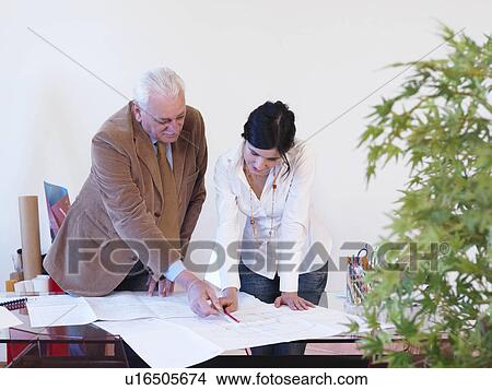 Picture - Co-workers standing at table. Fotosearch