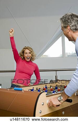 Stock Image - Couple having fun playing table football. Fotosearch