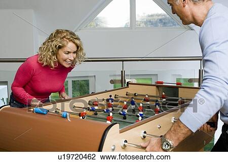 Stock Image - Couple having fun playing table football. Fotosearch