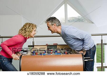 Stock Photo - Couple having fun playing table football. Fotosearch
