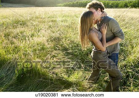 Couple kissing in a field View Large Photo Image Stock Image - Couple kissing in a field. Fotosearch
