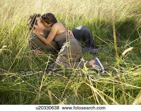 Couple kissing in a field View Large Photo Image Stock Photo - Couple kissing in a field. Fotosearch