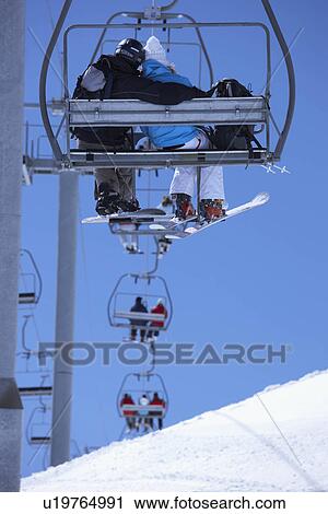 Stock Image - Couple sitting close in chair lift. Fotosearch