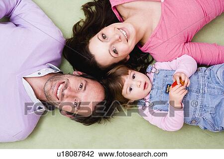 Stock Image - Family laying on carpet. Fotosearch