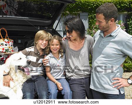 Stock Image - Family standing against their car. Fotosearch