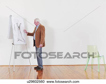 Stock Image - Fashion designer drawing onto flip chart. Fotosearch