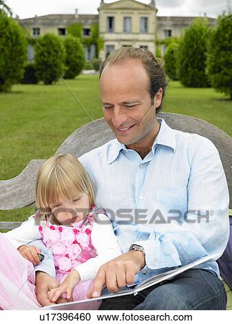 Stock Image - Father and daughter reading a book. Fotosearch