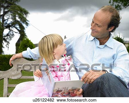 Stock Image - Father and daughter reading a book. Fotosearch