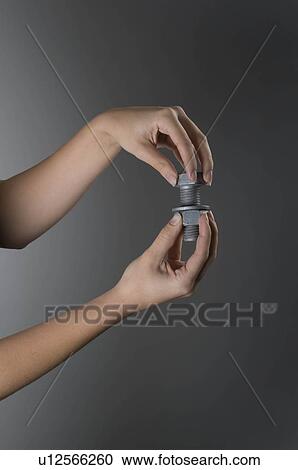 Stock Image - Female hands holding nut and bolt. Fotosearch
