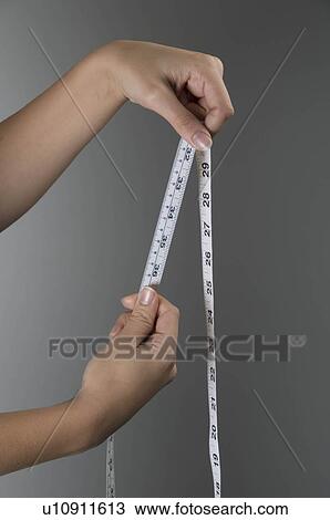 Stock Image - Female hands holding tape measure. Fotosearch