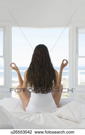 Female in yoga pose sitting on bed View Large Photo Image Stock Image - Female in yoga pose sitting on bed. Fotosearch