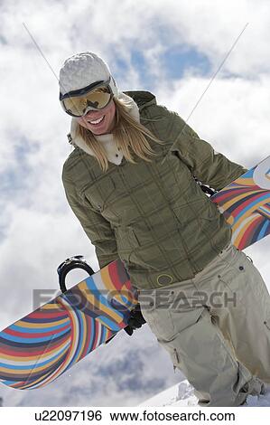 Stock Photograph - Female snowboarder walking with her snow. Fotosearch