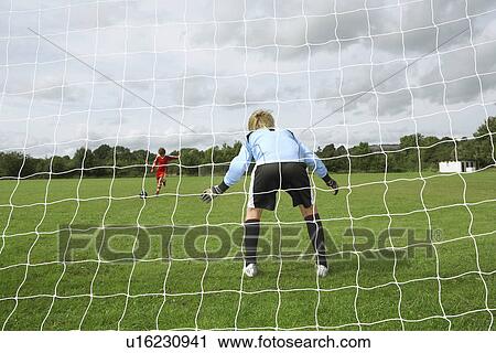 Stock Image - Footballer shooting at goalkeeper. Fotosearch