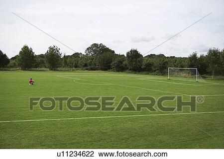 Stock Image - Footballer sitting looking at the goal. Fotosearch