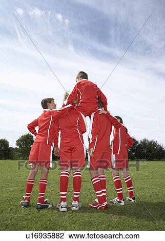 Stock Image - Footballer sitting on a teams shoulders. Fotosearch