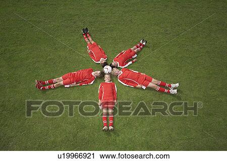 Stock Image - Footballers lying around a ball. Fotosearch