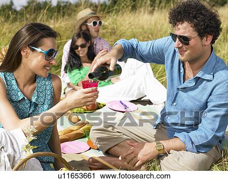 Friends having a picnic in a field View Large Photo Image Stock Image - Friends having a picnic in a field. Fotosearch
