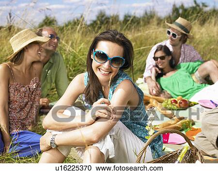 Friends having a picnic in a field View Large Photo Image Stock Image - Friends having a picnic in a field. Fotosearch
