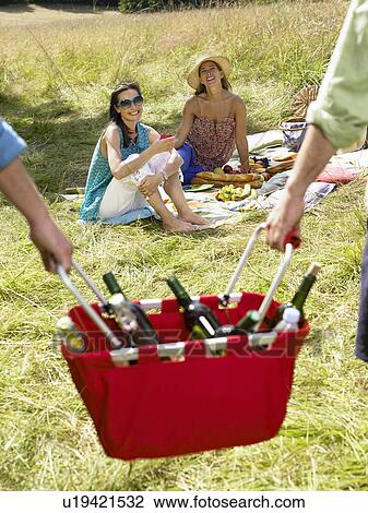 Friends having a picnic in a field View Large Photo Image Stock Image - Friends having a picnic in a field. Fotosearch