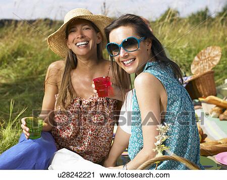Friends having a picnic in a field View Large Photo Image Stock Image - Friends having a picnic in a field. Fotosearch