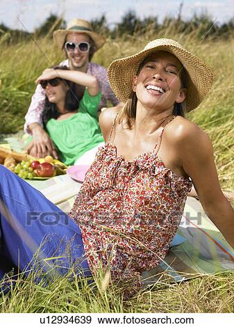 Friends having a picnic in a field View Large Photo Image Stock Photo - Friends having a picnic in a field. Fotosearch