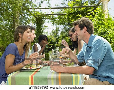 Stock Image - Friends having lunch in the garden. Fotosearch
