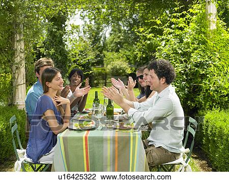 Stock Image - Friends having lunch in the garden. Fotosearch