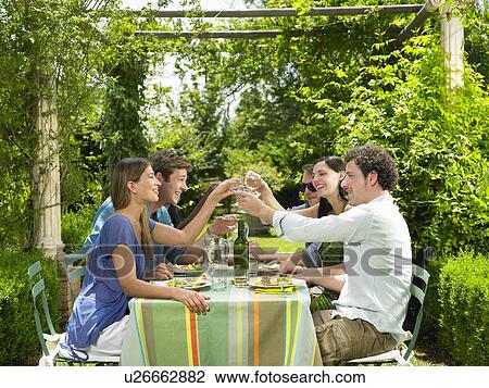 Stock Image - Friends having lunch in the garden. Fotosearch