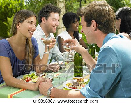 Stock Photo - Friends having lunch in the garden. Fotosearch