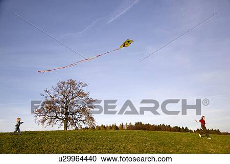Stock Image - Girl and Boy fly a Kite. Fotosearch