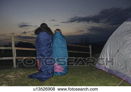 Stock Photo - Girl and boy in sleeping bags at dusk. Fotosearch