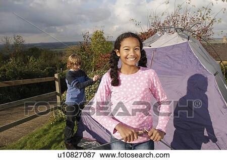 Stock Photo - Girl and boy putting up tent. Fotosearch