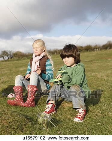 Stock Image - Girl and boy with toy planes in field. Fotosearch
