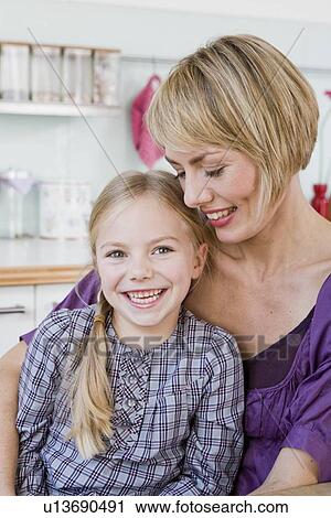 Girl and woman in a kitchen hugging View Large Photo Image Stock Image - Girl and woman in a kitchen hugging. Fotosearch