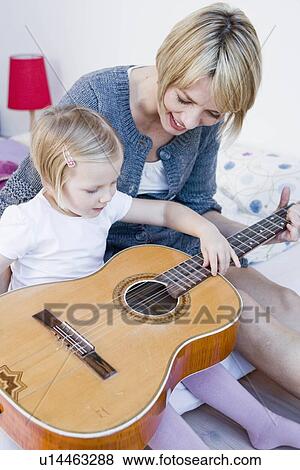 Stock Photo - Girl and woman playing with a guitar. Fotosearch