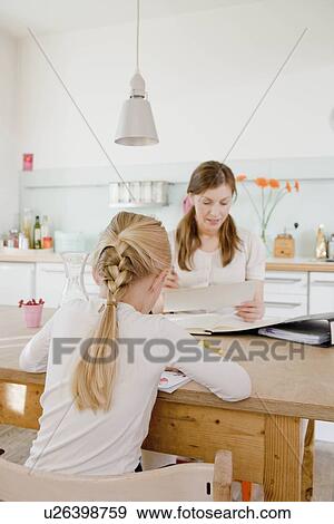 Stock Photo - Girl and woman sitting at table reading. Fotosearch