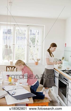 Girl and woman sitting at table working View Large Photo Image Stock Image - Girl and woman sitting at table working. Fotosearch