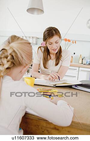 Stock Image - Girl and woman sitting at table writing. Fotosearch