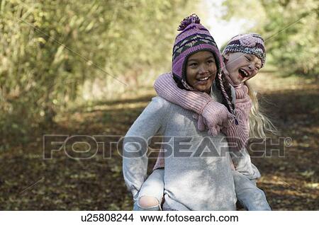 Girl carrying friend in countryside View Large Photo Image Picture - Girl carrying friend in countryside. Fotosearch