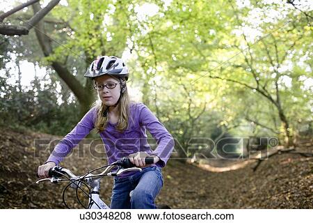 Stock Photo - Girl cycling in Forest. Fotosearch