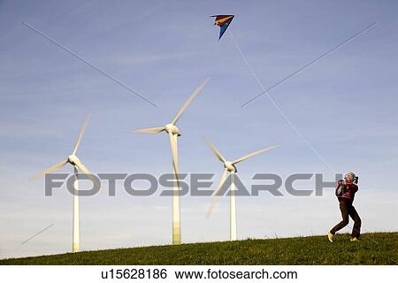 Stock Photograph - Girl Flying Kite at Wind Turbines. Fotosearch