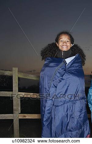 Picture - Girl in sleeping bag at dusk. Fotosearch