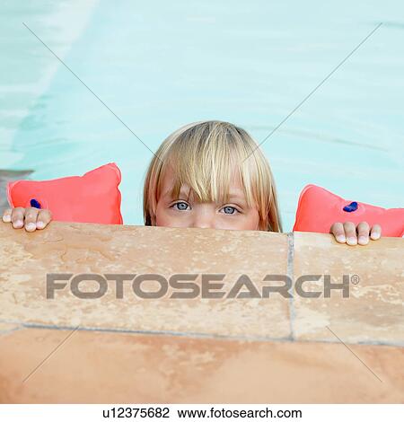 Stock Image - Girl in swimming pool with rubber rings. Fotosearch