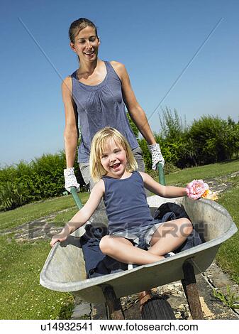 "Girl in wheelbarrow, pushed by a woman" View Large Photo Image Stock Image - "Girl in wheelbarrow, pushed by a woman". Fotosearch