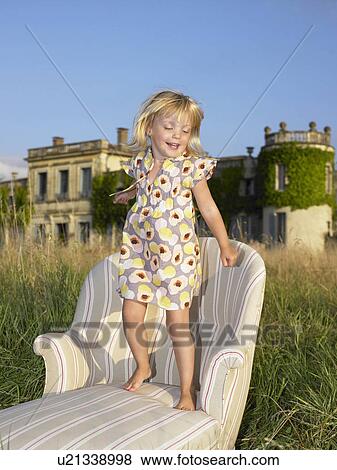Girl jumping on sofa in a field View Large Photo Image Stock Photo - Girl jumping on sofa in a field. Fotosearch