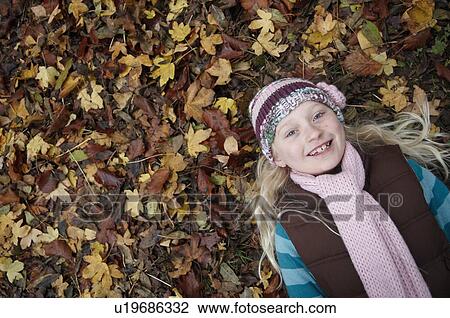 Stock Image - Girl lying on autumn leaves. Fotosearch