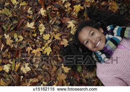 Stock Photography - Girl lying on autumn leaves. Fotosearch